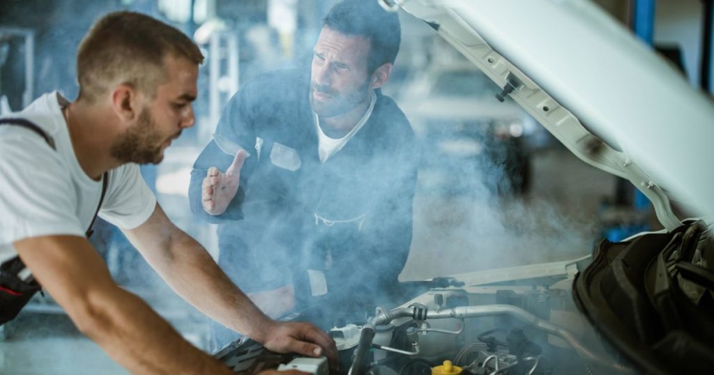 auto mechanics talking while working on overheated car engine in a workshop